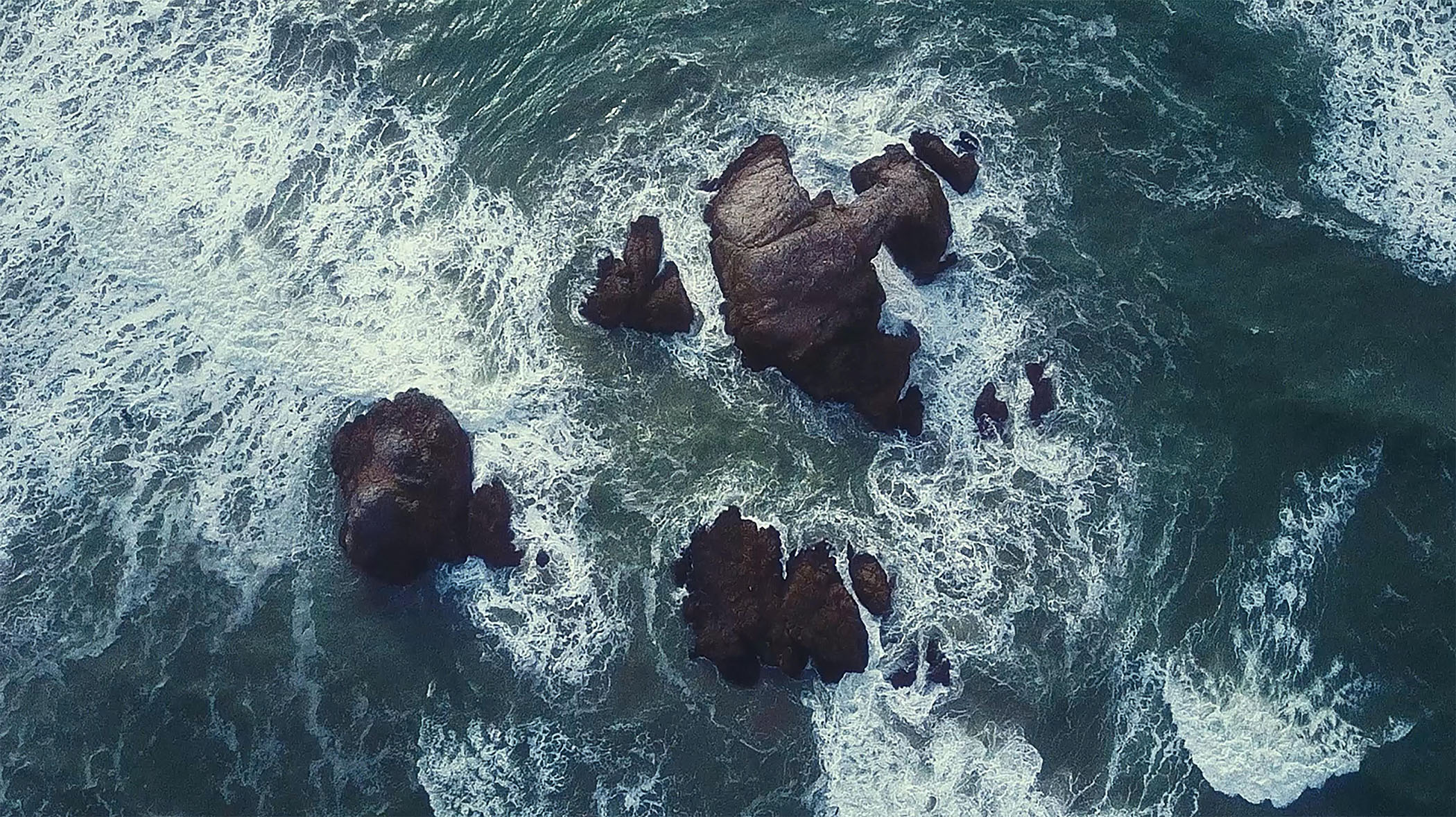 top view of waves crashing on rocks